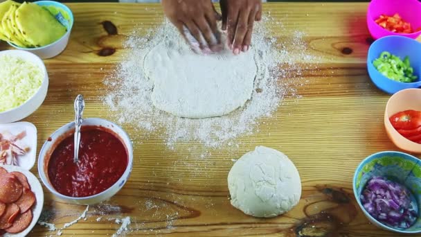 Top view on man by hands making pizza dough round on yellow wooden table — Stock Video