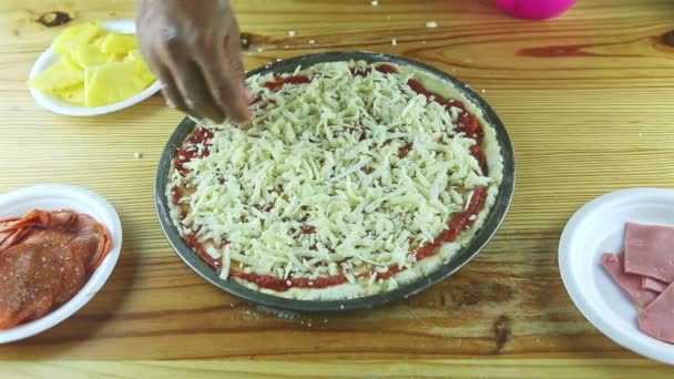 Top view closeup on man hands put grated hard cheese on pizza with tomato sauce — Stock Video