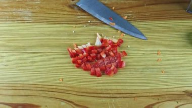 Bıçakla insan ellerine tepeden bakıldığında taze salataya kırmızı dolma biber parçaları konur.
