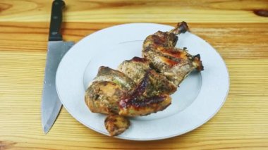 Erkek ellerinin üst görüntüsü beyaz tabağın yanına bıçak ve kızarmış tavuğun yarısını koyar.