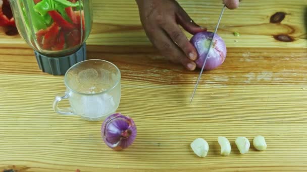 Widok z góry na ręce człowieka nożem wyciąć całą fioletową cebulę na połówki na drewnianym stole — Wideo stockowe