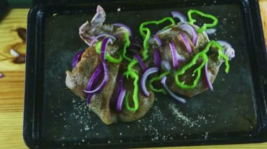 Erkek elinin en üst görüntüsü, çiğ tavuğun yarısıyla birlikte siyah fırın tabağı tutuyor.