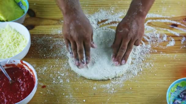 Górny widok na człowieka przez ręce co ciasto pizzy duże i cienkie nad drewnianym stole — Wideo stockowe