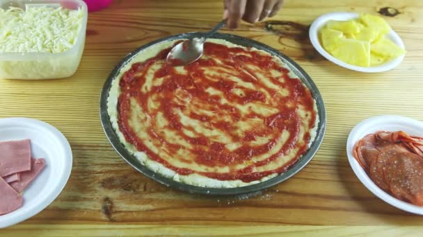 Вид зверху на руки людини накласти шматочки цибулі на півфінішну піцу з соусом і сиром — стокове відео