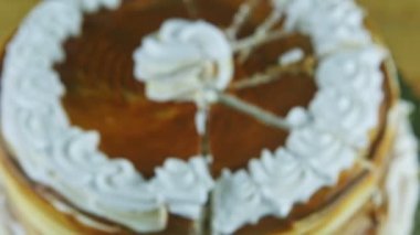 Karamelli pastaya odaklan. Beyaz kremayla süslenmiş. Parçalara ayrılmış.