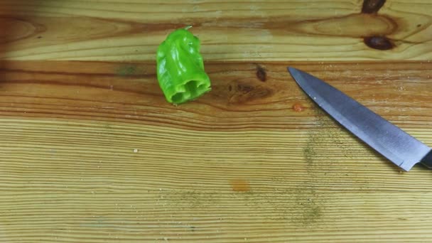 Top view closeup στο μισό πράσινο πιπέρι με μεγάλο μαχαίρι σε ξύλινο τραπέζι — Αρχείο Βίντεο