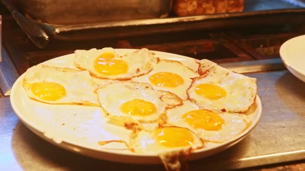 Panorama de primer plano en gran plato blanco con muchos huevos fritos con yemas amarillas — Vídeos de Stock