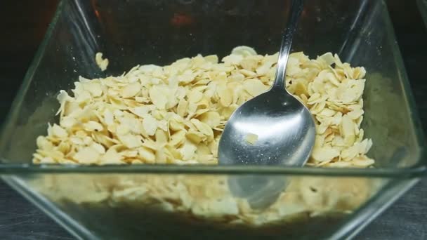 Panorama de primer plano en un recipiente de vidrio profundo con rodajas de almendras secas servidas con cuchara grande — Vídeos de Stock