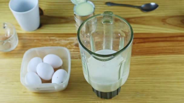 Alejarse lentamente del cáliz blander de vidrio con leche, huevos blancos y latas de acero — Vídeos de Stock