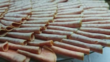 Büyük siyah tabakta yakın plan panorama. Yemek katında çeşitli jambon dilimleri var.