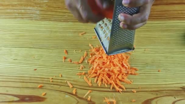 Top view close-up op man door handen rasp kleine schijfjes rijpe wortel op metalen rasp — Stockvideo