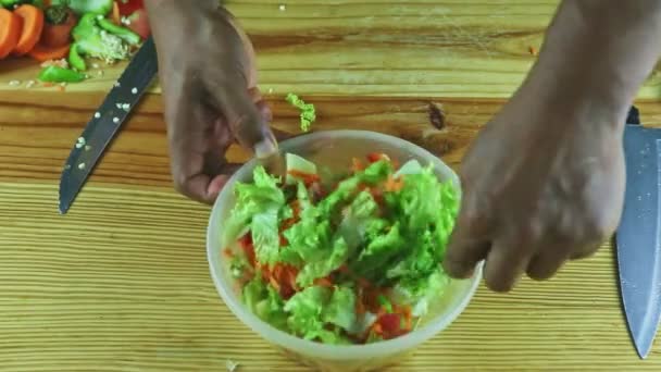 Top view on man hands by big spoon mix chopped vegetables in plastic bowl — Stock Video