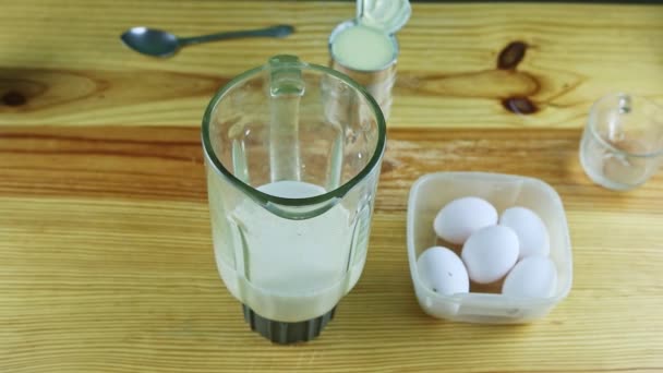 Bovenaanzicht op mens door handen giet dagelijkse melk in blender kelk met gecondenseerde melk — Stockvideo