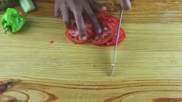 İnsan ellerinin üst görüntüsü. Tahta masa üzerinde bıçakla kesilmiş domates dilimleri. — Stok video