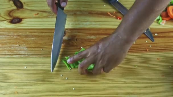 Vista dall'alto sulle mani dell'uomo tagliate a coltello su pezzi grandi fette di pepe verde — Video Stock
