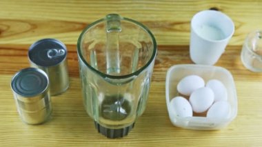 Erkek ellerine yukarıdan bakınca beyaz bardaktan masaya cam kadehe süt dökülüyor.