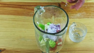 Üst kattaki yakın plan çekimde cam bardaktan blender kadehine temiz su dökülüyor