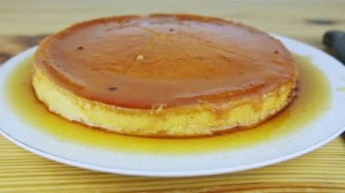 Beyaz tabakta karamel şurubuyla dilimlenmiş yumuşak turtayı yavaşça yakınlaştır.