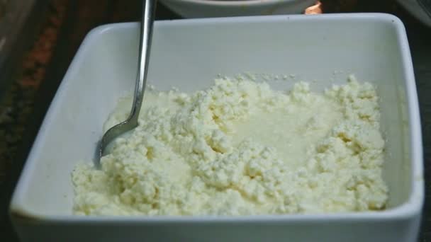 Closeup panorama at grainy fresh cottage cheese served in deep white bowl — Stock Video