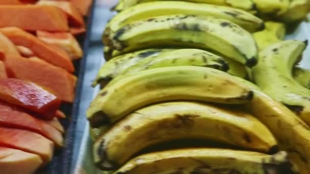 Panorama de primer plano de plato plano con plátanos maduros a plato negro con rodajas de papaya — Vídeo de stock