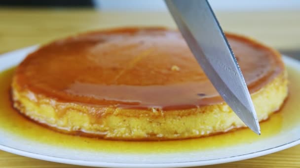 Closeup man hands by knife start to cut round soft flan with caramel syrup — Stok Video