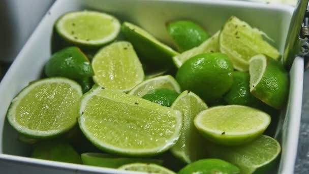 Vista de cerca en el tazón blanco con mitades de cal verde jucy en el surtido patio de alimentos — Vídeos de Stock