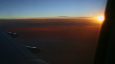 Güzel günbatımında çelik kanat silueti boyunca uçak penceresinden hava manzarası