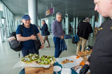 LVIV, UKRAINE - 24 Mayıs 2018 Birçok yolcu 24 Mayıs 'ta Lviv havaalanı salonundaki ücretsiz dezenfekte masasından atıştırmalık ve içecek denedi
