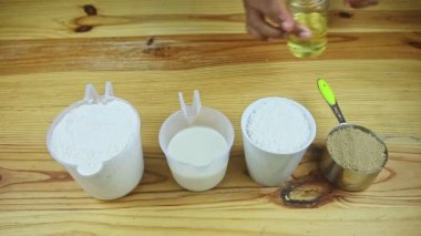 Üst görüşlü adam elleri zeytinyağlı cam kavanozu birçok farklı malzemenin yanına koyar.