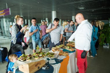 LVIV, UKRAINE - 24 Mayıs 2018: farklı yolcular 24 Mayıs 'ta Lviv havaalanı salonundaki ücretsiz degustation masasından atıştırmalıkları denedi