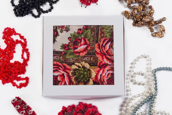 Bovenaanzicht op kleine witte geschenkdoos met zachte katoenen sjaal met rood bloemsieraad Stockfoto