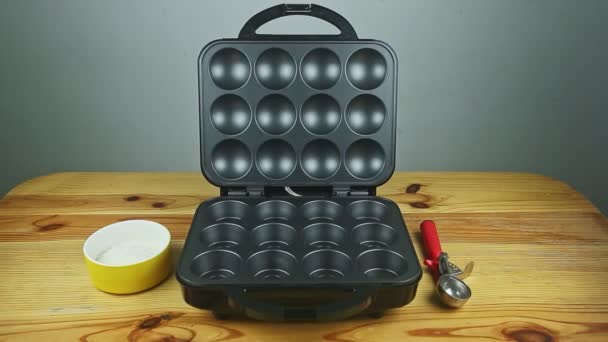 Mesin panggang hitam besar terbuka untuk muffin yang dibuat disajikan di meja kayu kuning — Stok Video