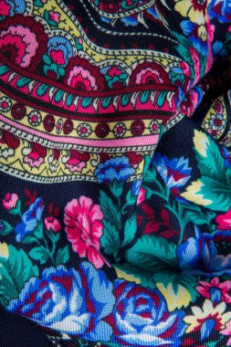 Üst görüntü katlanmış koyu mavi pamuklu atkıya renkli çiçek süsüyle yakın plan.
