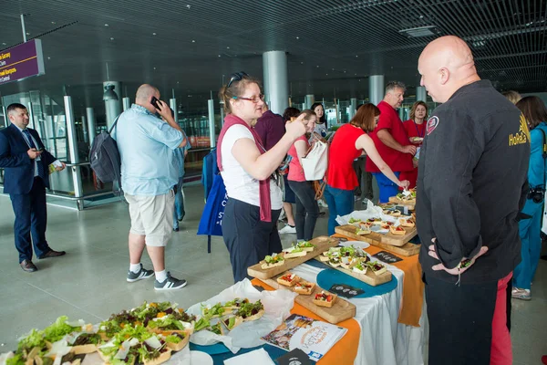 Muitos passageiros experimentam lanches e bebidas da mesa de degustação gratuita no salão do aeroporto de Lviv Fotografia De Stock