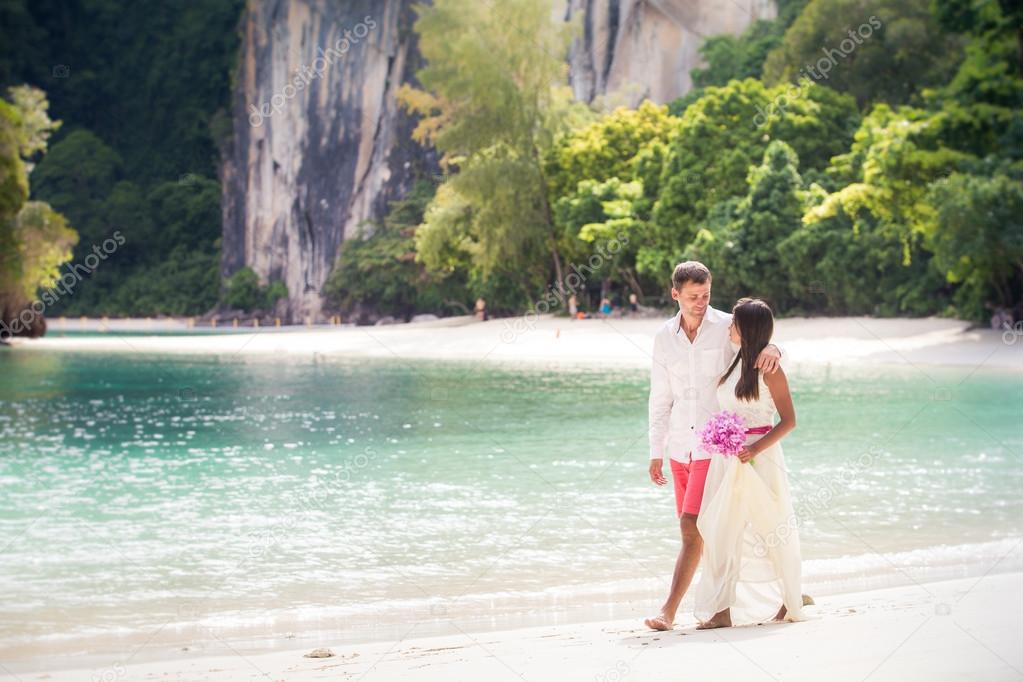 Handsome groom with pretty bride on beach