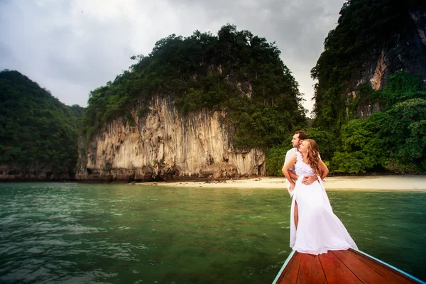 Groom embrace bride sitting on longtail boat — Stock Photo, Image