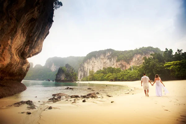 Невеста и жених ходят босиком по песчаному пляжу — стоковое фото