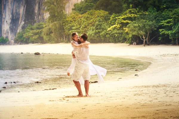 Невеста и жених кружатся и целуются на песчаном пляже — стоковое фото