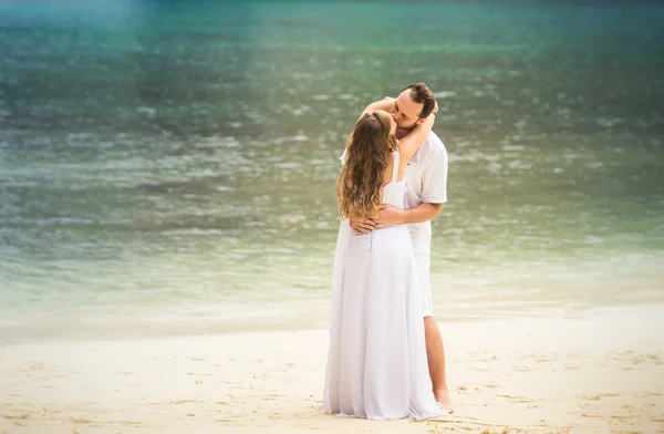 Bionda sposa e sposo bacio in piedi sulla spiaggia di sabbia — Foto Stock