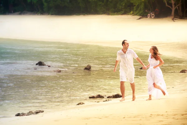 Sposa e sposo correre a piedi nudi sulla spiaggia di sabbia — Foto Stock