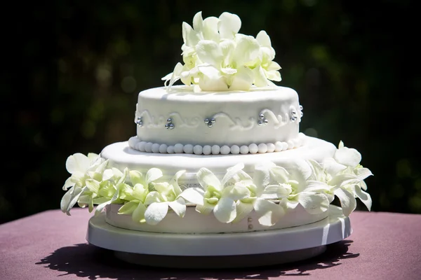 Nagy fehér esküvői torta, fehér orchideák és pe elölnézete — Stock Fotó