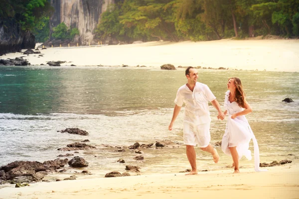 Braut und Bräutigam laufen am Strand — Stockfoto