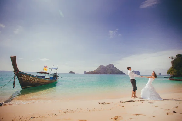 Bruden och brudgummen håller händerna på stranden — Stockfoto