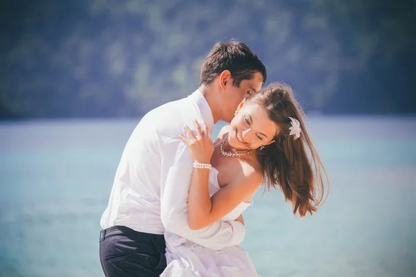 Groom embracing bride on beach — Stock Photo, Image