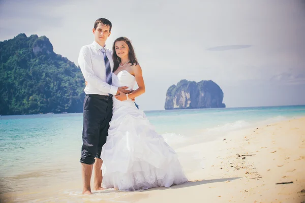 Brudgummen och bruden på sandstrand — Stockfoto