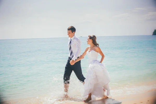 Bride and groom run sandy beach — Stock Photo, Image