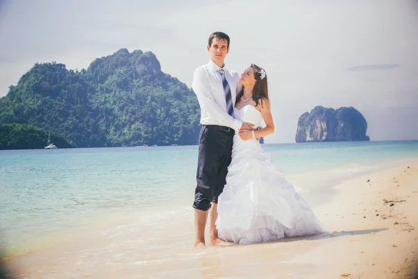 Sposo tenere sposa in piedi sulla spiaggia di sabbia — Foto Stock