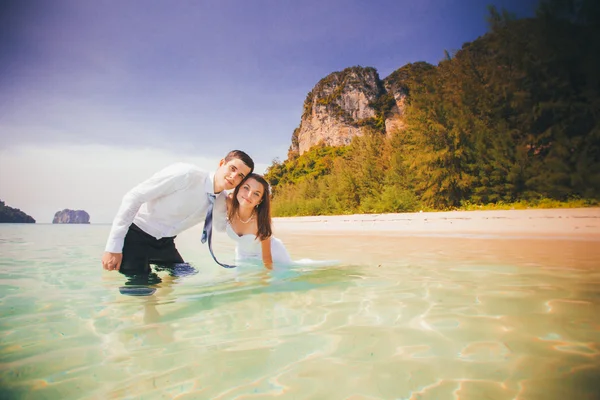 Bride and groom embrace half in shallow water — Stock Photo, Image