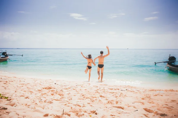 Menina e cara correr para o mar azul — Fotografia de Stock