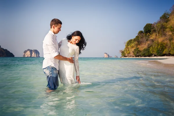 Bruden och brudgummen kram hälften i öppet vatten — Stockfoto